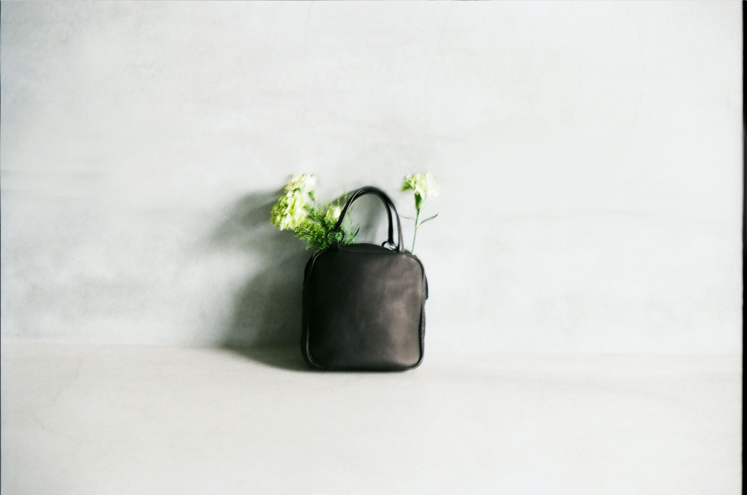 small deer leather bag made from natural materials with flowers on minimal background