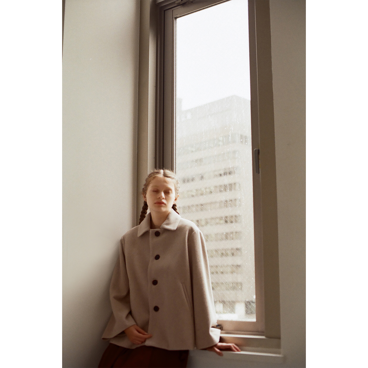 Mochi 2026 Autumn Winter image look featuring a light beige wool coat by the window with soft natural light.