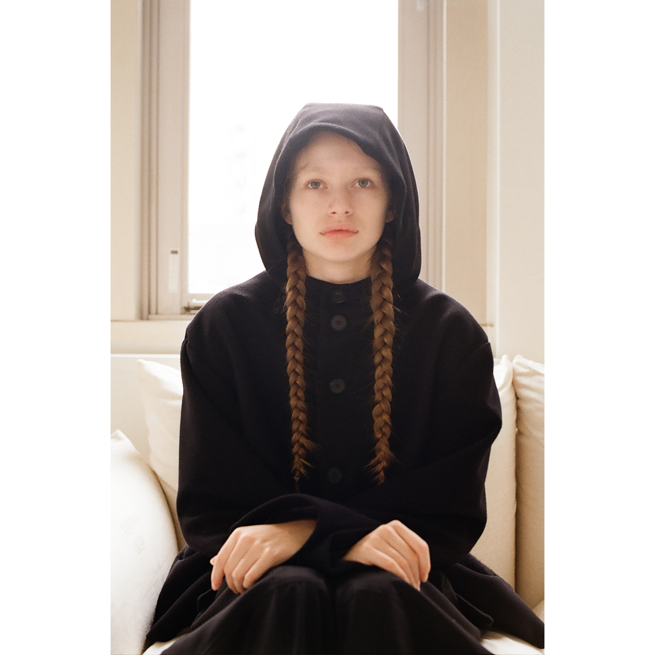 Portrait of a model wearing a black hooded coat in the Mochi 2026 Autumn Winter image look.