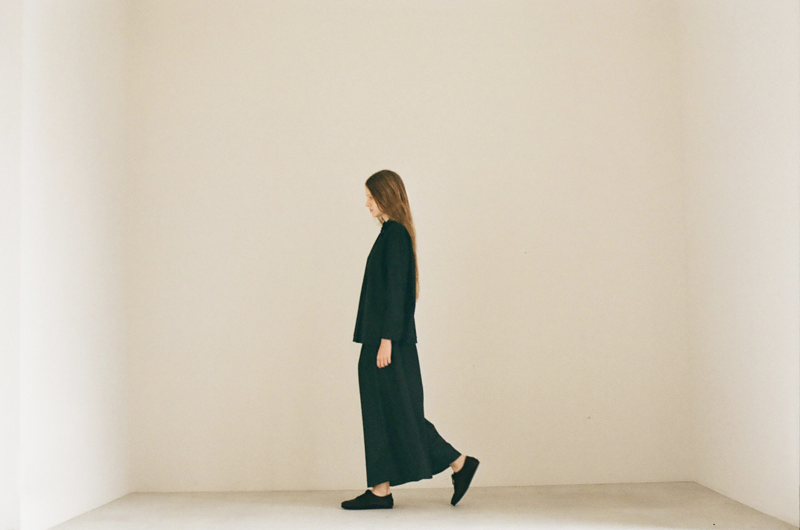 Mochi 2026 Autumn Winter image look 08 featuring a model walking in a relaxed black set-up.