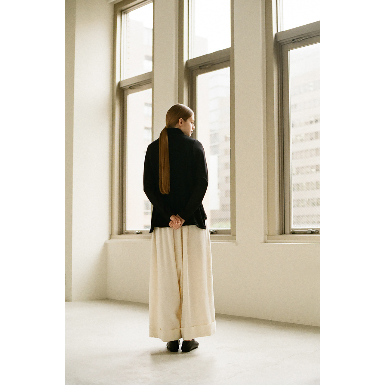 Back view of a black knit and ivory wide pants in the Mochi 2026 Autumn Winter image look.